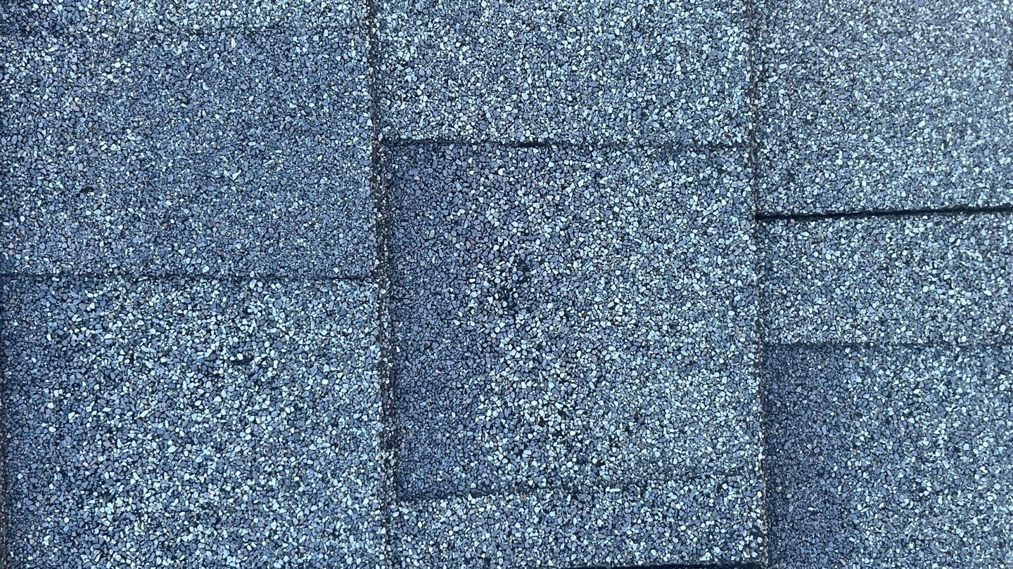 Dislodged shingle edge documented before the roof replacement in Sherman, TX