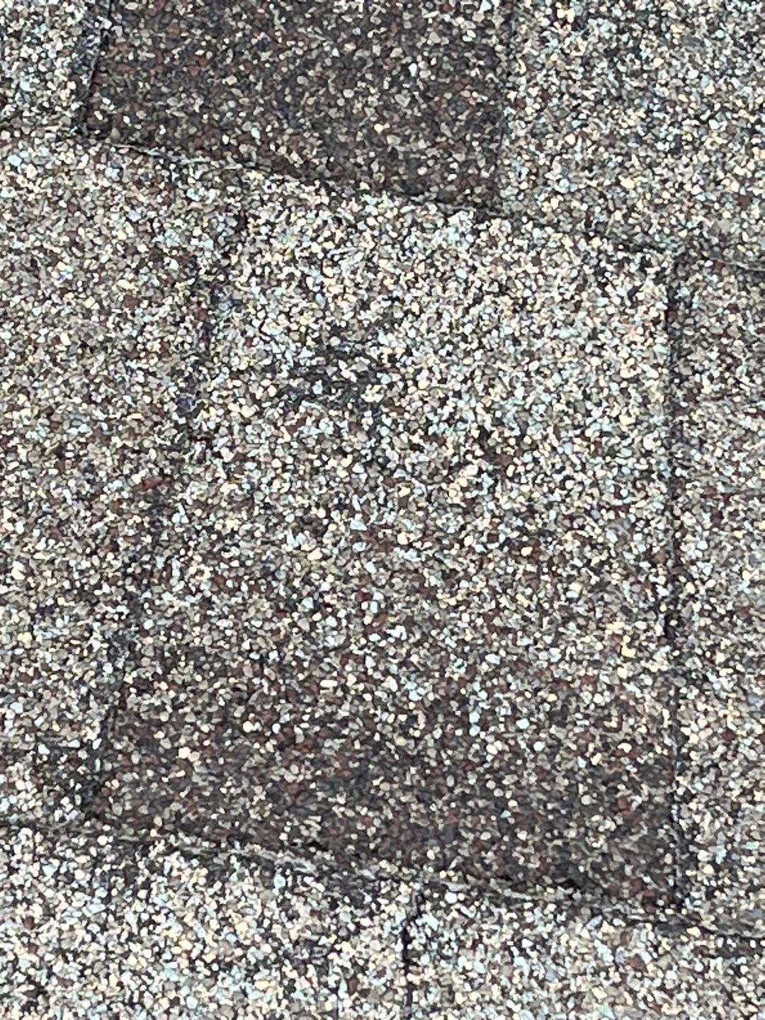 Wind-lifted shingle edge showing hail impact before the roof replacement in Prosper, TX