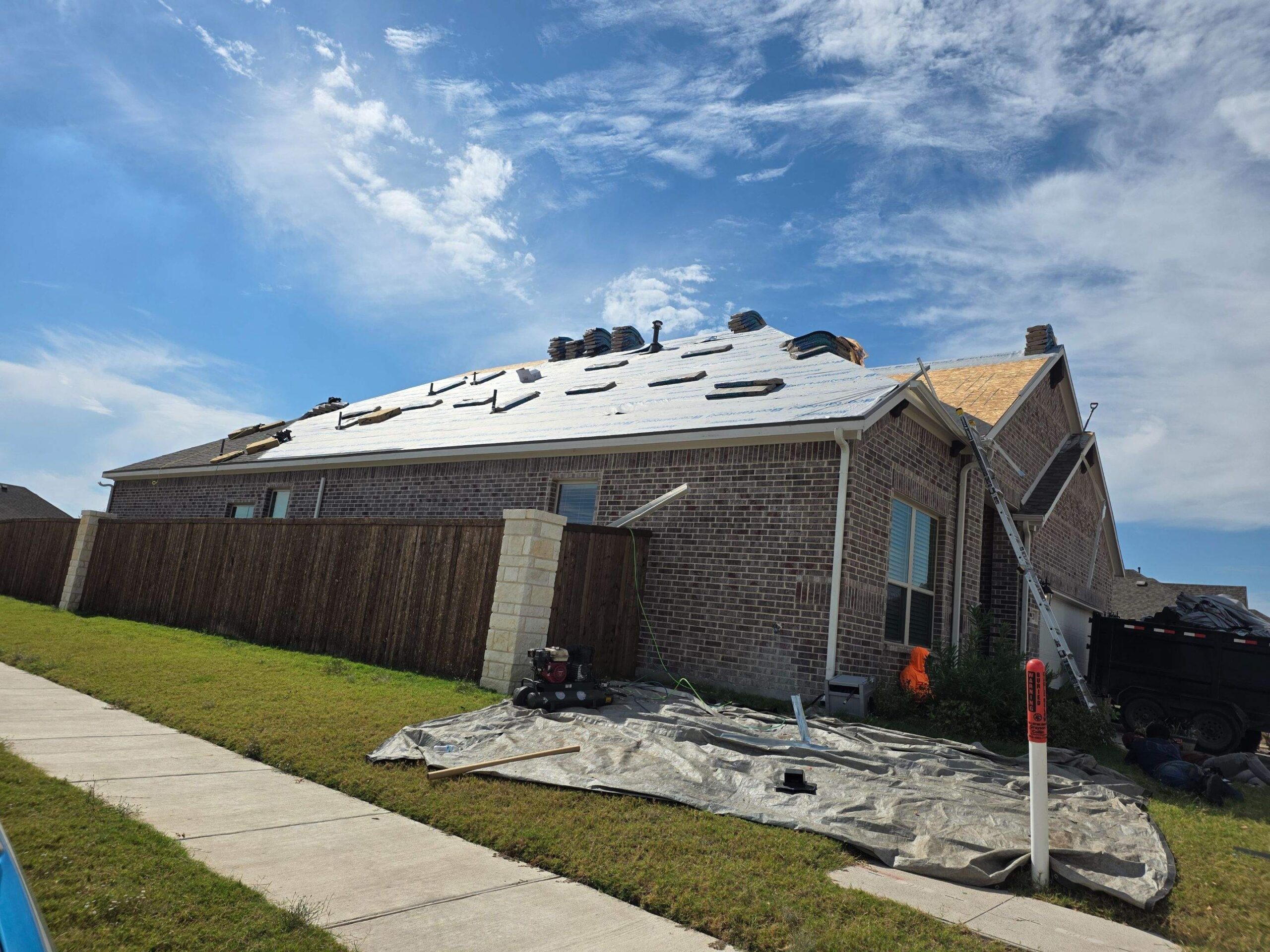 During roof replacement in Anna: crew completing shingle installation near the roof ridge