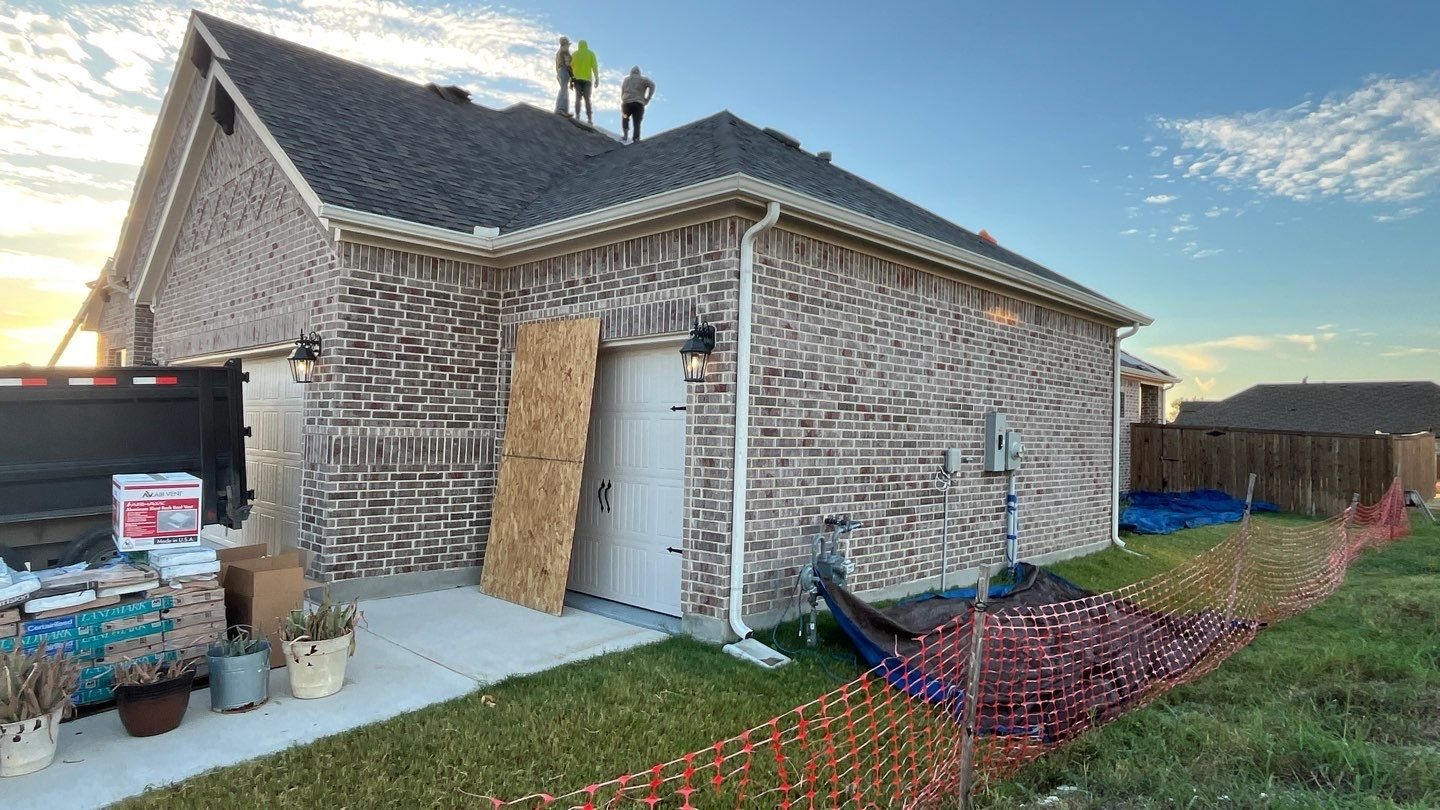 During roof replacement in Anna: crew rolling out synthetic underlayment across the steep roof plane