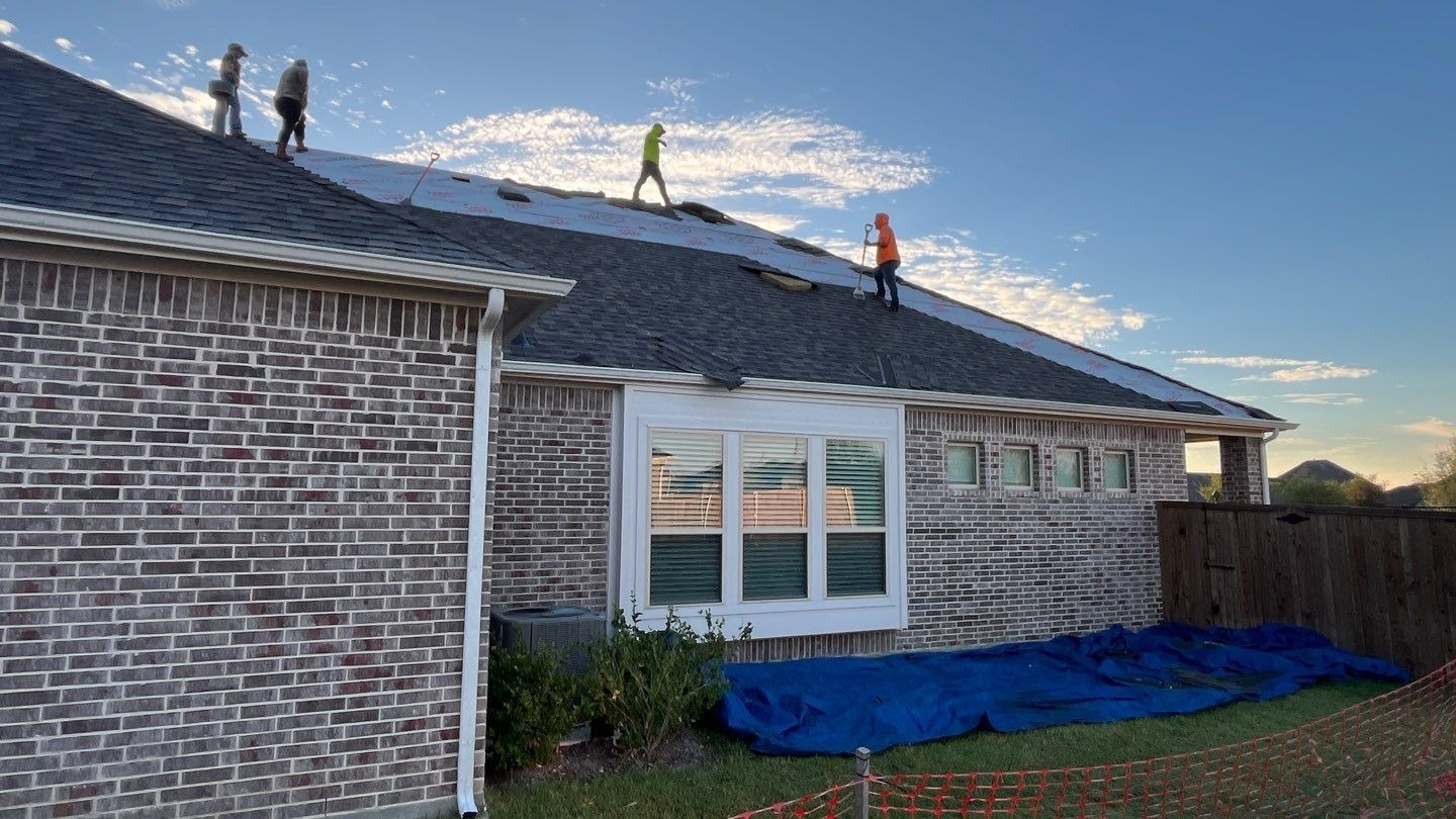 During roof replacement in Anna: underlayment installation continues across another section of the roof
