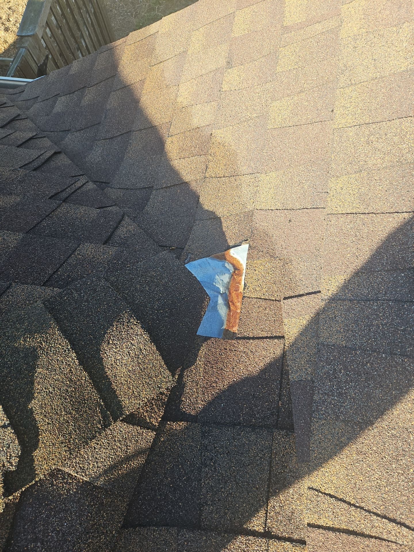 Before roof repair in Anna with close-up view of damaged ridge line shingles