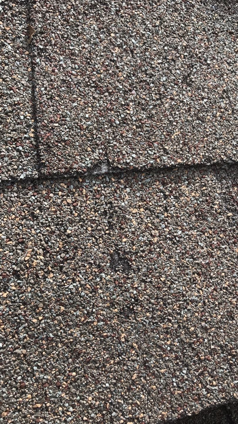Cracked shingle mat exposed by hail impact ahead of the roof replacement in Melissa, TX